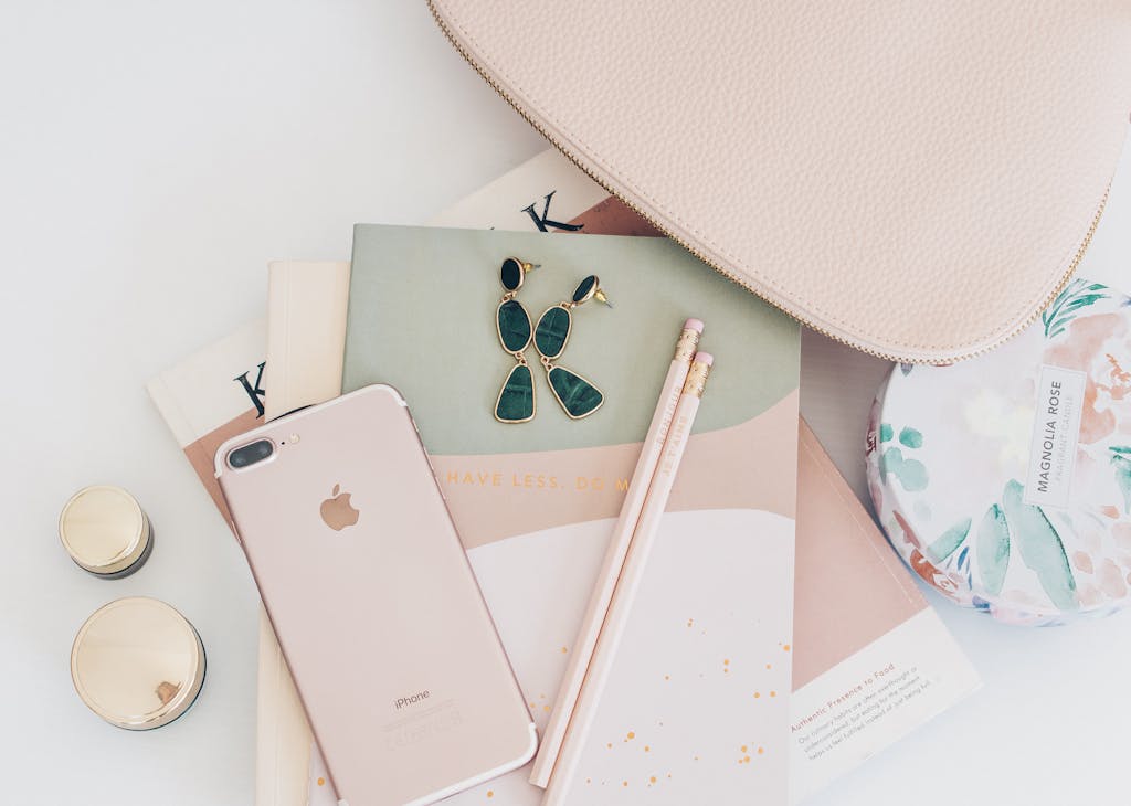 A stylish flatlay featuring rose gold accessories, an iPhone, and a notebook, perfect for a feminine fashion theme.